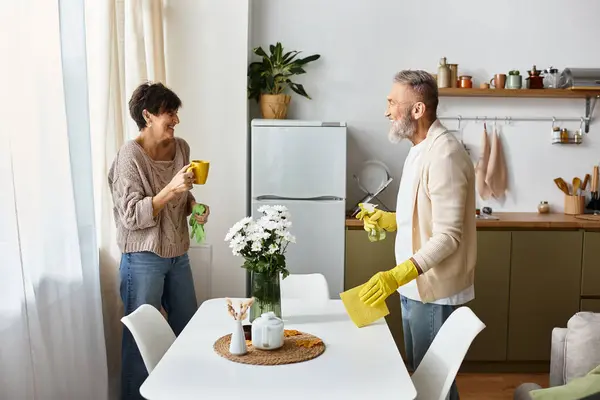 A joyful couple engages in cleaning together, laughing while enjoying each others company. — Stock Photo