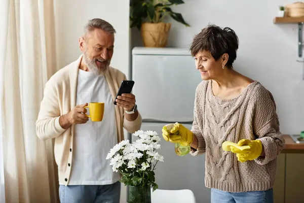 Em uma cozinha quente, um casal sorri enquanto limpam e compartilham momentos alegres um com o outro. — Fotografia de Stock