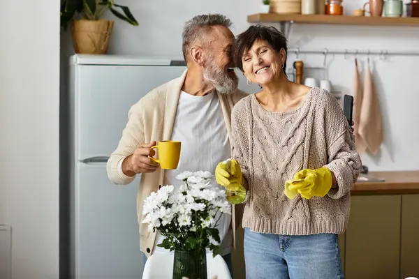 A senior couple shares laughter and love while tending to flowers in their cozy kitchen. — Stock Photo