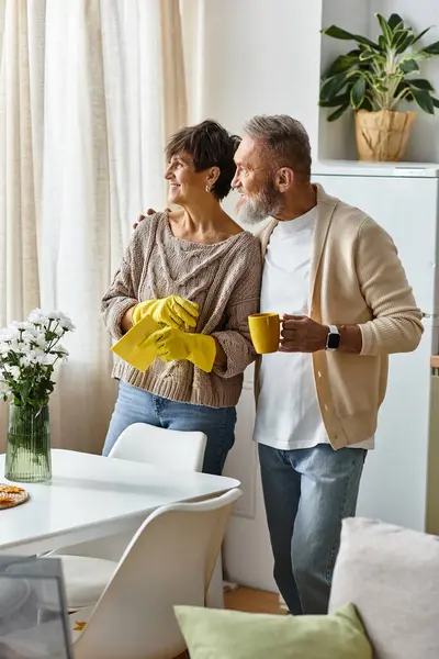 A happy couple shares tea and laughs while tidying up their bright living room. — Stock Photo