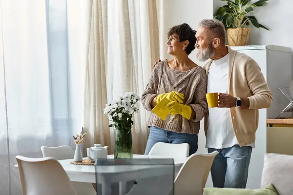 A happy couple stands together in their cozy kitchen, sharing a joyful moment with tea. — Stock Photo