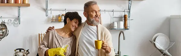 Um homem e uma mulher compartilham um abraço caloroso em sua cozinha lindamente arranjada enquanto desfrutam de café. — Fotografia de Stock