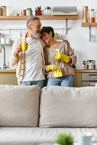 A mature couple shares a warm moment in the kitchen while cleaning up and enjoying each other. — Stock Photo