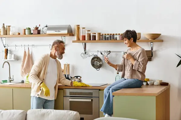 Joyful moments shared as a mature couple interacts while working in their modern kitchen — Stock Photo