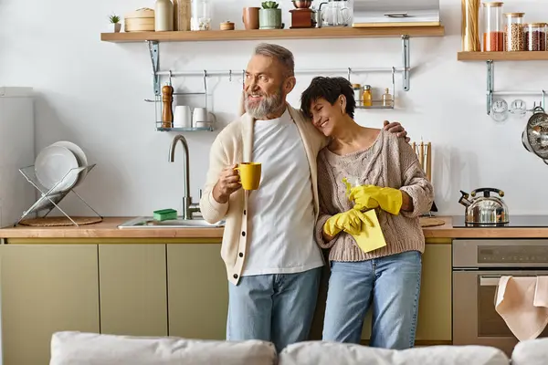 Una pareja cariñosa comparte un momento tierno mientras ordenan su cocina alegre juntos - foto de stock
