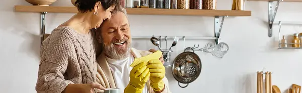 A happy couple enjoys each others company as they clean together in their inviting kitchen space. — Stock Photo