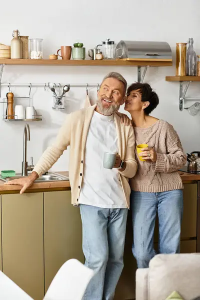 A couple shares laughter and warm drinks in their stylish kitchen at home. — Stock Photo
