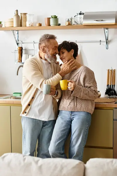 Um casal maduro compartilha um momento quente em sua cozinha moderna enquanto desfruta de café juntos. — Stock Photo