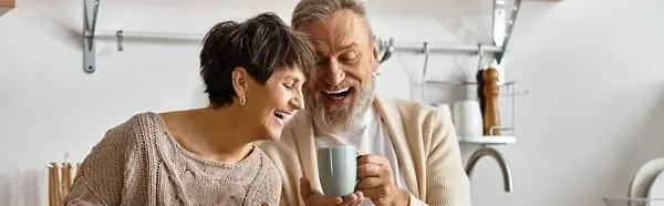 Casal feliz compartilhando um momento de luz enquanto toma café em sua cozinha moderna. — Fotografia de Stock