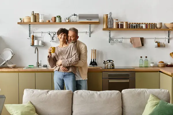 Una coppia matura condivide un momento caldo nella loro cucina elegante, sorridendo e gustando drink. — Foto stock