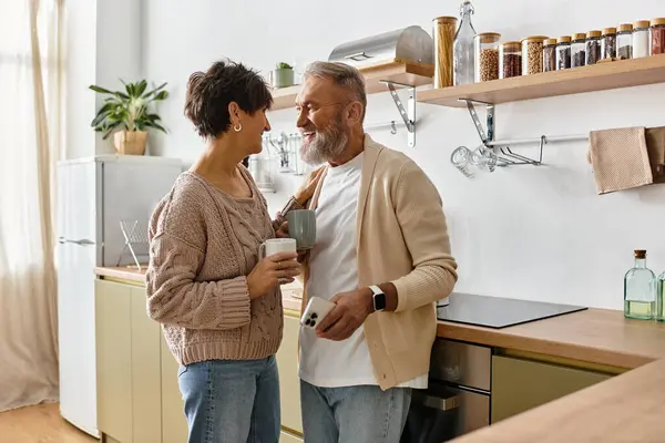 A mature couple enjoys each others company while chatting and smiling in their inviting kitchen. — Stock Photo