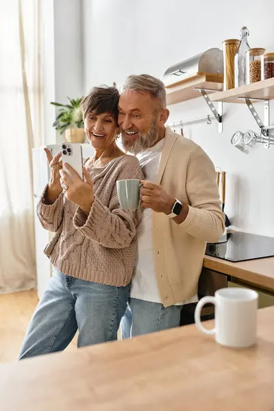 Um casal desfruta de um momento alegre juntos enquanto segura bebidas em sua cozinha elegante. — Fotografia de Stock