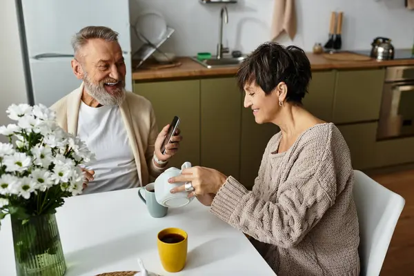 Un couple d'âge mûr joyeux partage un moment de rire tout en dégustant un café ensemble. — Photo de stock