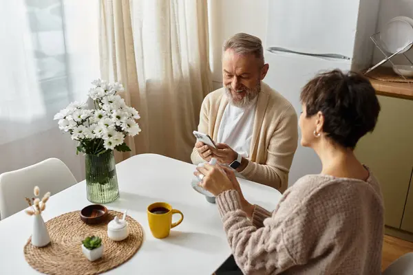 Um casal maduro compartilha momentos pacíficos ao café enquanto explora seus telefones juntos. — Fotografia de Stock