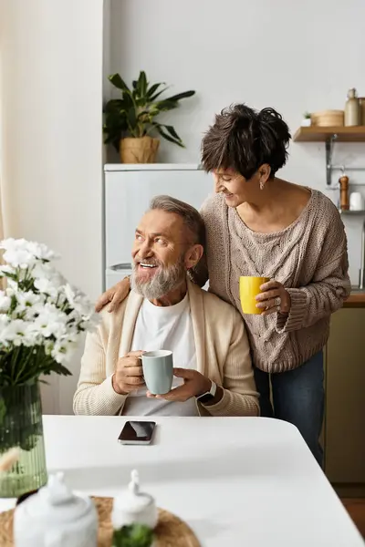 A couple shares laughter and warmth while sipping coffee in their charming kitchen space. — Stock Photo