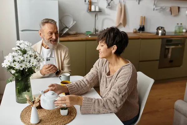 Two seniors share delightful conversation while preparing tea in a bright, inviting kitchen. — Stock Photo