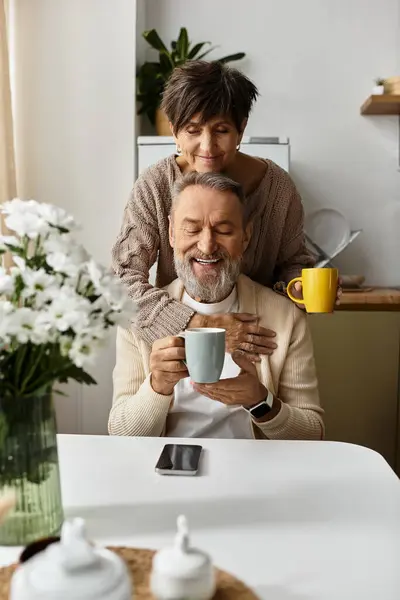 Una pareja madura disfruta del café felizmente en su cálida y encantadora cocina. - foto de stock