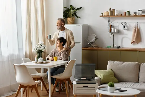A mature man holds a cup of coffee while sharing a moment with his partner at breakfast. — Stock Photo