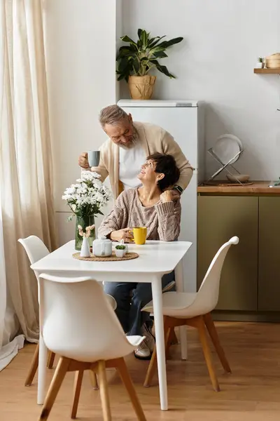 A couple shares a joyful moment over coffee in a bright kitchen, surrounded by warmth and love. — Stock Photo