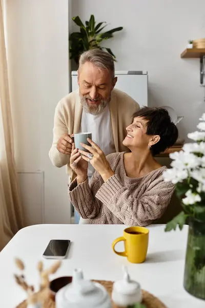 Senior couple shares a warm moment over coffee in their bright, inviting kitchen space. — Stock Photo
