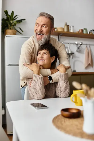 A happy man embraces a smiling woman while they share a joyful moment in a cozy kitchen. — Stock Photo
