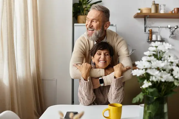 A mature couple enjoys quality time together, smiling and sharing affectionate gestures at home. — Stock Photo