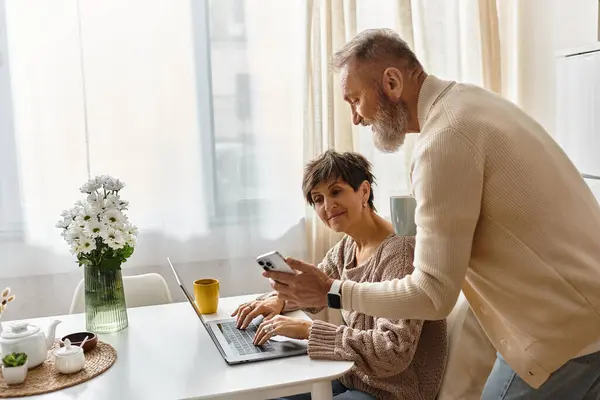 Mature couple enjoys each others company with a laptop and phone in their cozy home. — Stock Photo