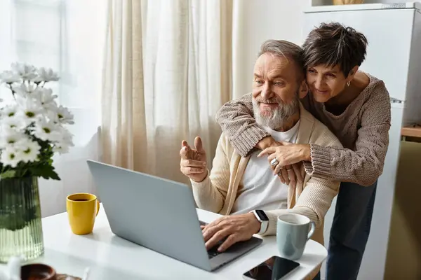 A mature couple enjoys quality time together, engaging with a laptop and each other happily. — Stock Photo