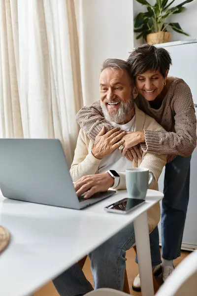 A joyful senior couple shares a lovely moment, laughing as they interact with a laptop. — Stock Photo