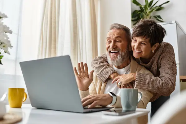 A mature couple shares laughter and warmth as they engage in an online conversation at home. — Stock Photo