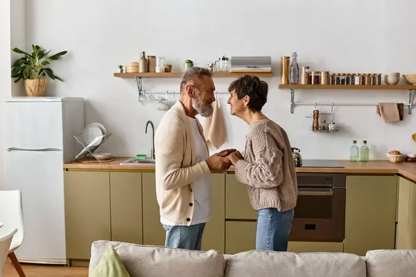 Two seniors engage in a playful exchange, enjoying a lighthearted moment in their modern kitchen. — Stock Photo