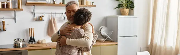 A senior couple enjoys a tender hug in their beautifully decorated kitchen, filled with warmth. — Stock Photo