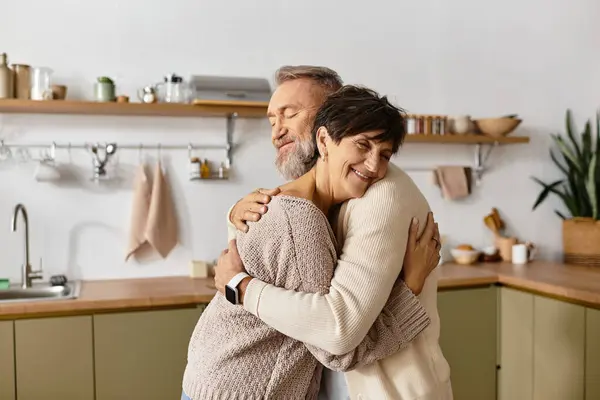 Two seniors express love and affection while hugging in a bright, inviting kitchen. — Stock Photo