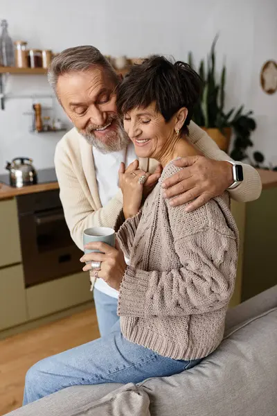 A senior couple laughs together while sipping coffee in their stylish, inviting living space. — Stock Photo
