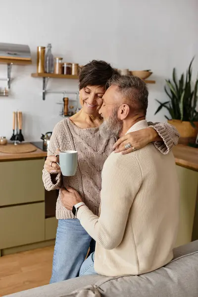 A loving couple embraces warmly, enjoying coffee together in a stylish kitchen. — Stock Photo