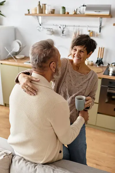 Femme et homme profitant de l'autre compagnie tout en sirotant du café dans leur cuisine accueillante. — Photo de stock