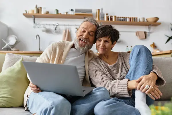 A joyful mature couple relaxes together, sharing a light hearted moment and laughter indoors. — Stock Photo