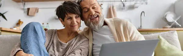Two happy seniors share laughter and smiles as they watch something together on a laptop. — Stock Photo
