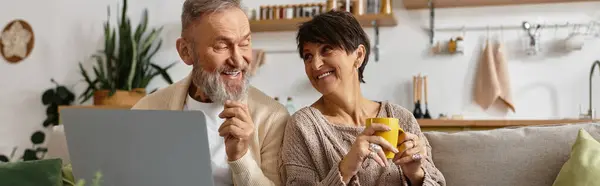 A couple enjoys joyful moments, sipping drinks and smiling together in their cozy home. — Stock Photo