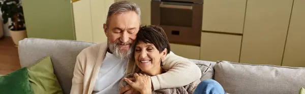 A couple enjoys a warm embrace on a comfortable sofa, sharing laughter and connection. — Stock Photo