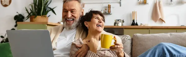 Couple rires et liens sur des expériences partagées tout en sirotant un café sur un canapé confortable. — Photo de stock