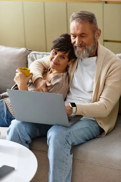 Couple enjoys time together on the couch while browsing the laptop, filled with smiles and warmth. — Stock Photo