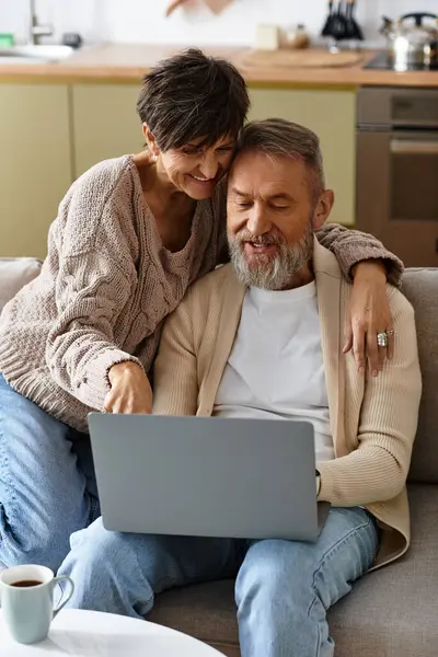 A happy senior couple shares laughs and love while browsing online from their cozy sofa. — Stock Photo