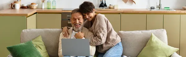 Зріла пара насолоджується компанією один одного під час перегляду фільму на ноутбуці вдома. — стокове фото