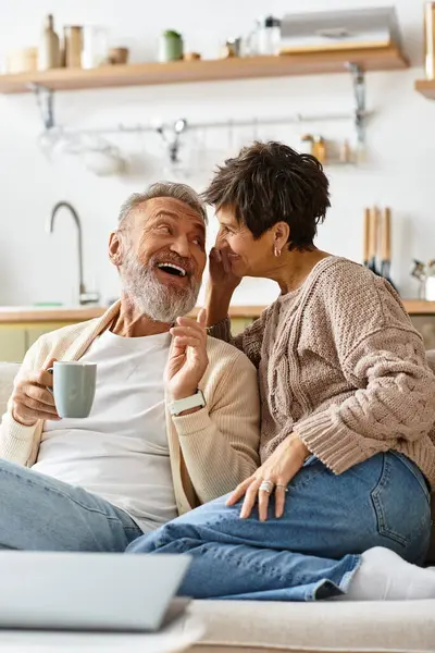 Un hombre y una mujer disfrutan de una conversación de corazón ligero mientras toman café en su casa. - foto de stock