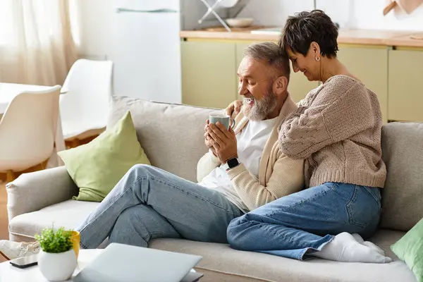 Uomo e donna condividono un pomeriggio gioioso sul divano, esplorando i contenuti insieme nella loro casa. — Foto stock