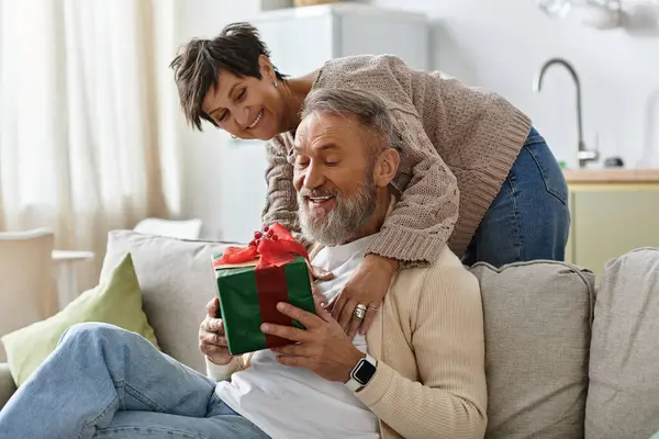 Couple enjoys a heartfelt moment as the woman gifts her partner a beautifully wrapped present. — Stock Photo