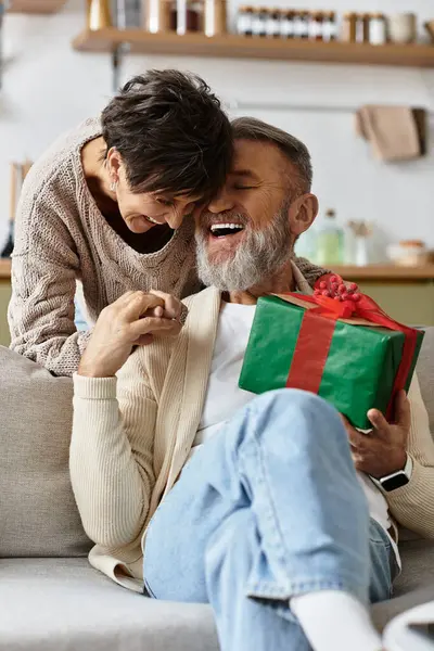 A couple shares a heartfelt moment exchanging a gift on a cozy day. — Stock Photo