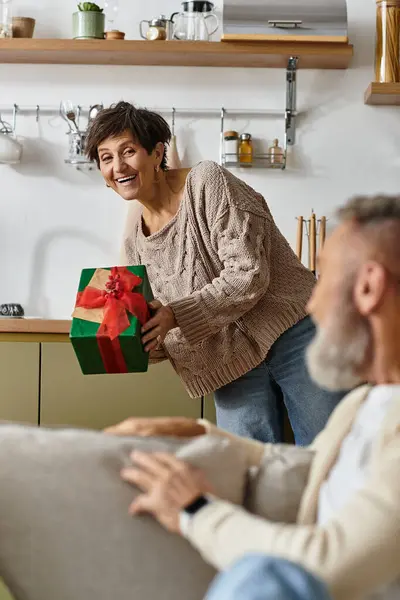 Couple shares a heartwarming moment as the woman presents a beautifully wrapped gift to the man. — Stock Photo
