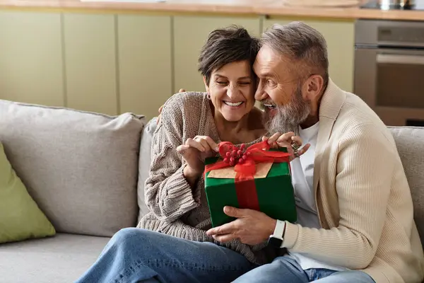 Happy couple embraces the moment while exchanging a beautifully wrapped gift together at home. — Stock Photo